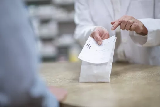 Pharmacist holding out prescription drug package