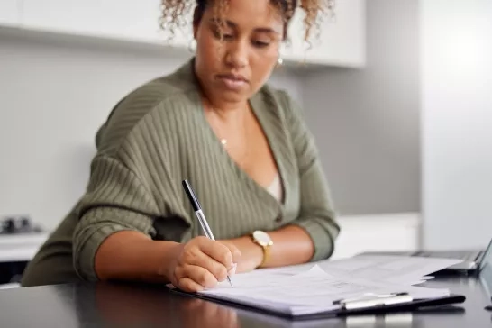 Woman filling paperwork at home in the kitchen