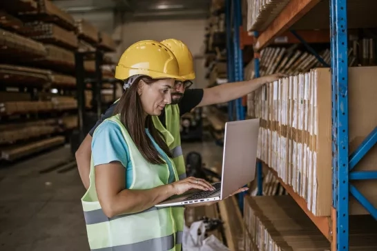 Warehouse workers checking inventory on laptop