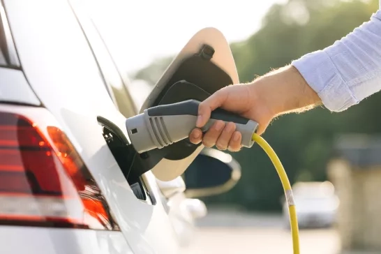 man attaching power cable to electric car