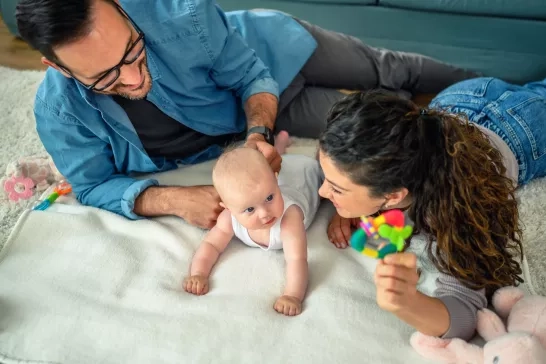 young parents playing with their baby girl at home