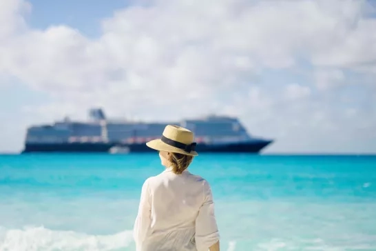 Woman standing on Half Moon Cay looking afar at a Holland America Line ship