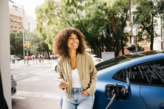 Woman standing next to her ev at a charging station