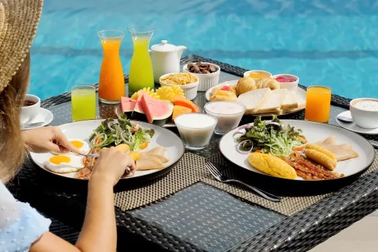 woman eating breakfast next to the pool