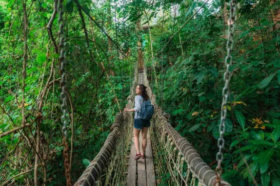 Woman walking on a rope bridge through the jungle in Costa Rica