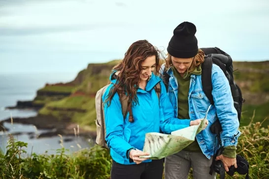 Two young travellers looking at a map on a hike in Ireland.