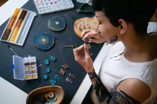 woman using pliers while making epoxy jewelry
