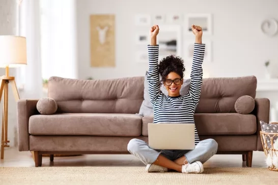 woman celebrating good news while working on laptop