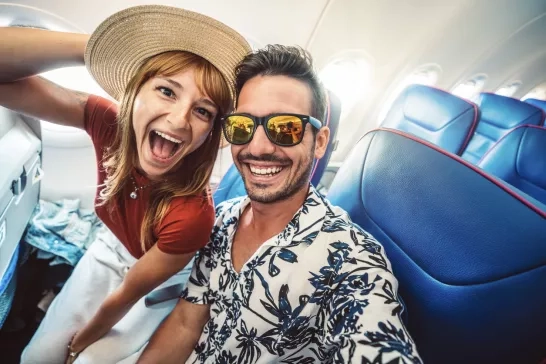 Happy tourist taking selfie inside airplane cheerful couple on vacation