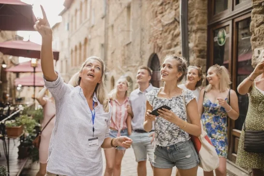 Group of people standing in a street in Volterra. They're listening to a tour guide who is talking about the architecture and the history.