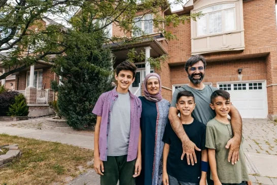 Family of 5 posing for picture in front of house.