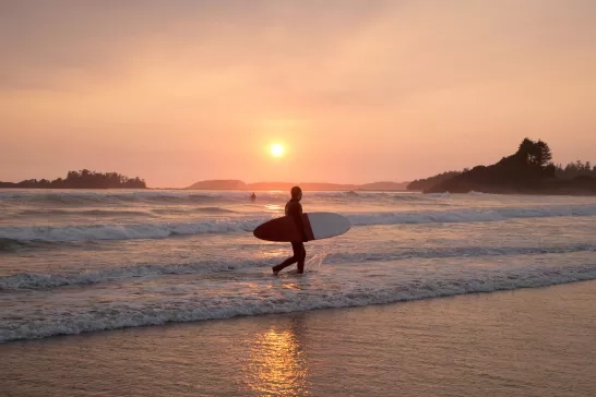 Surfer leaves ocean at sunset