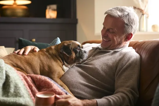 Man at home with a cup of tea and his dog