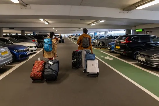 two people with luggage in airport parking lot