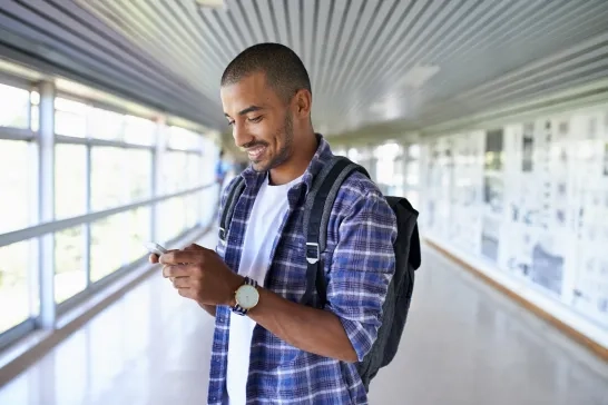 Man standing with a backpack holding a phone