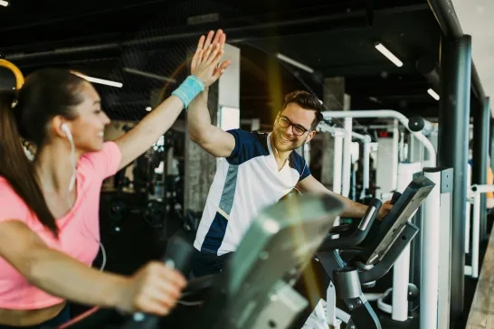 Man and woman fitness gym riding cycling machines 