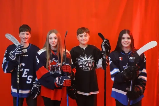Four young hockey players pose before a red background