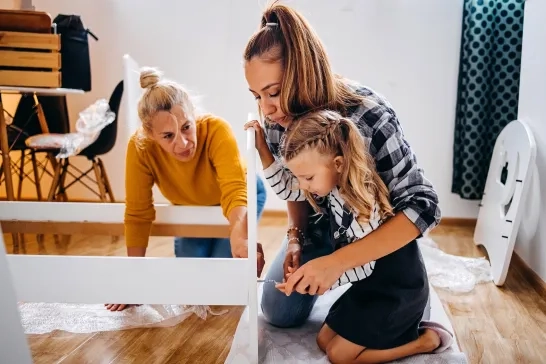 Mother, daughter, and grandmother putting together bed in a new home