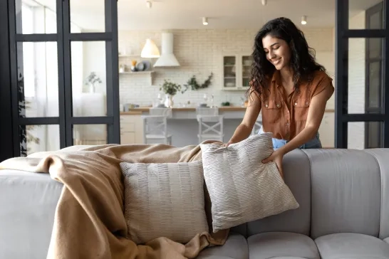 Woman placing cushion on sofa