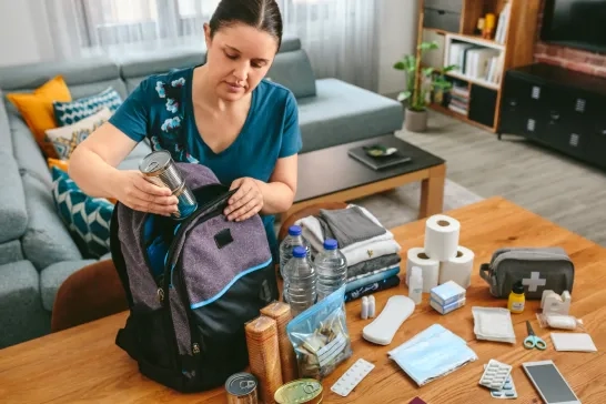 Woman putting cans of food to prepare emergency kit
