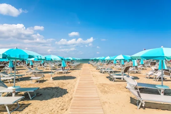 Beach chairs and umbrellas in Rimini, Italy during summer day with blue sky
