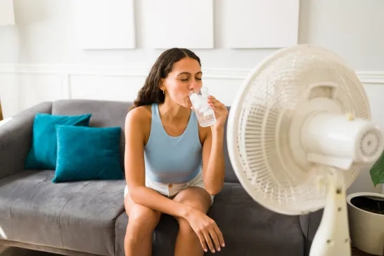 Woman enjoying a cold drink in front of the fan