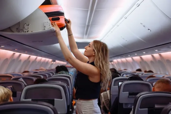 Passenger putting hand baggage in overhead bin on airplane