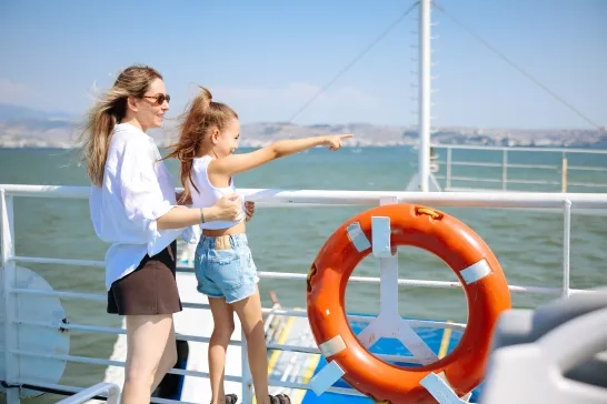 Little girl traveling by ship with her mother and looking seagull