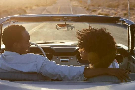 Rear view of couple on road trip in convertible at sunset