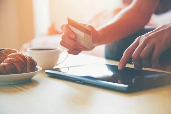 Person holding credit card and using tablet