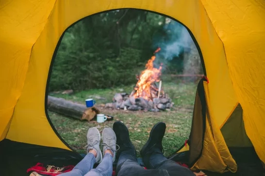 couple resting in tent with view on fire