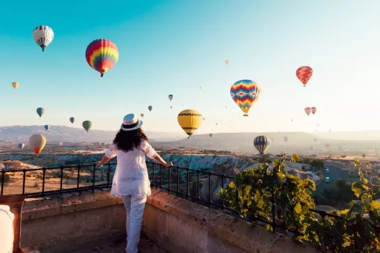 woman watching colorful hot air balloons flying over the valley at Cappadocia, Turkey.Turkey Cappadocia fairytale scenery of mountains. Turkey Cappadocia fairytale scenery of mountains.