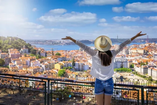 A happy tourist woman overlooks the colorful old town Alfama of Lisbon city