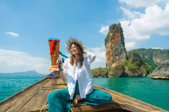 Cheerful woman traveling with Thai taxi boat and photographing with point and shoot camera