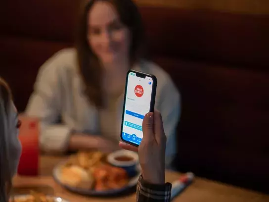 Woman looks at Swiss Chalet savings in CAA Mobile App