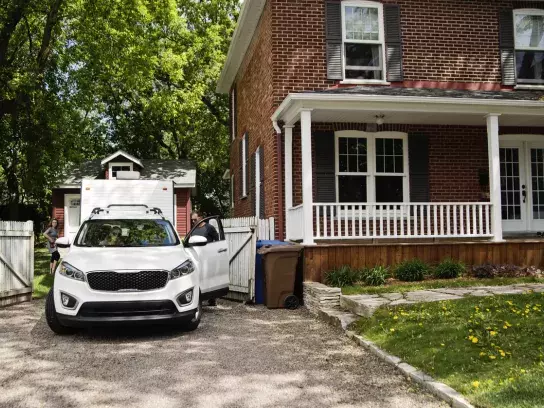 Family getting into their car parked in driveway of house