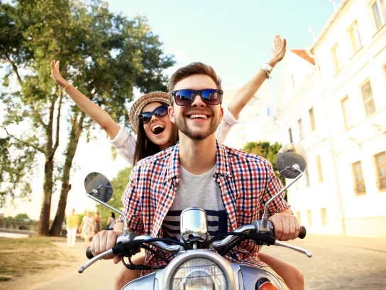 Happy young couple on scooter enjoying road in Italy