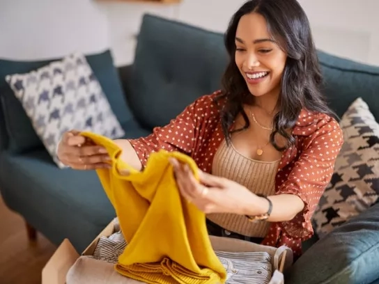 Woman opening yellow sweater online shopping order