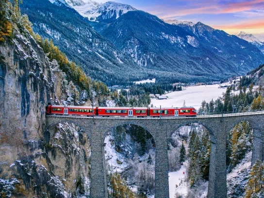 Aerial view of Train passing through famous mountain in Filisur, Switzerland. Landwasser Viaduct world heritage with train express in Swiss Alps snow winter scenery.