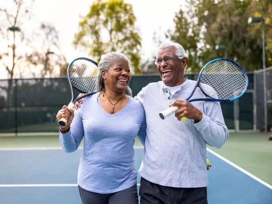 Senior couple walking off tennis court