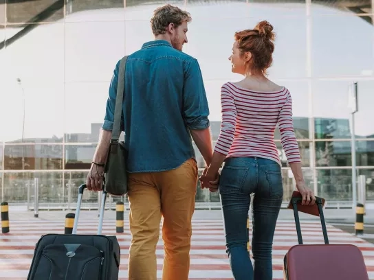 Young Couple walking with suitcases into airport leaving on vacation Young Couple walking with suitcases into airport leaving on vacation