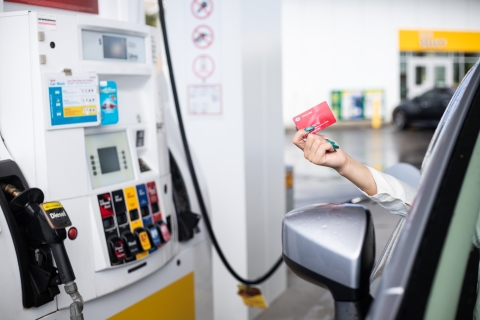 woman holding her membership card in front of gas pump