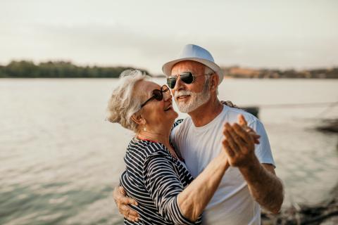 senior couple and smiling man and woman standing in sea and dancing