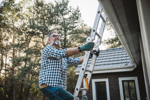 man climbing ladder to get on home roof