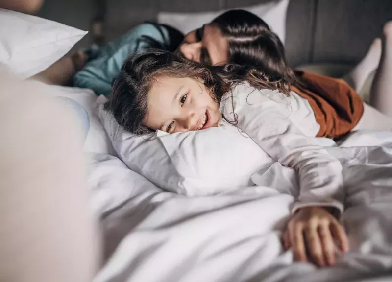 Family with child laying on hotel bed