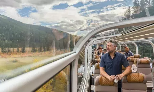 Man standing onboard Rocky Mountaineer looking out glass dome coach