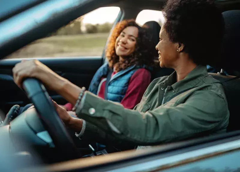 Two women driving in a car on the road