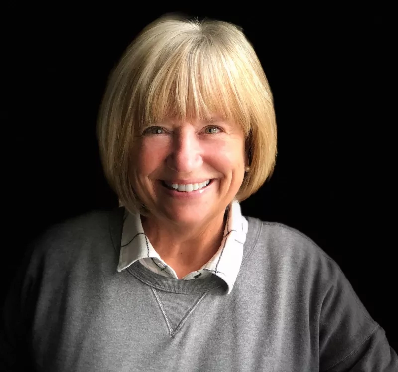 image of a white woman smiling at the camera infrom of a black backdrop