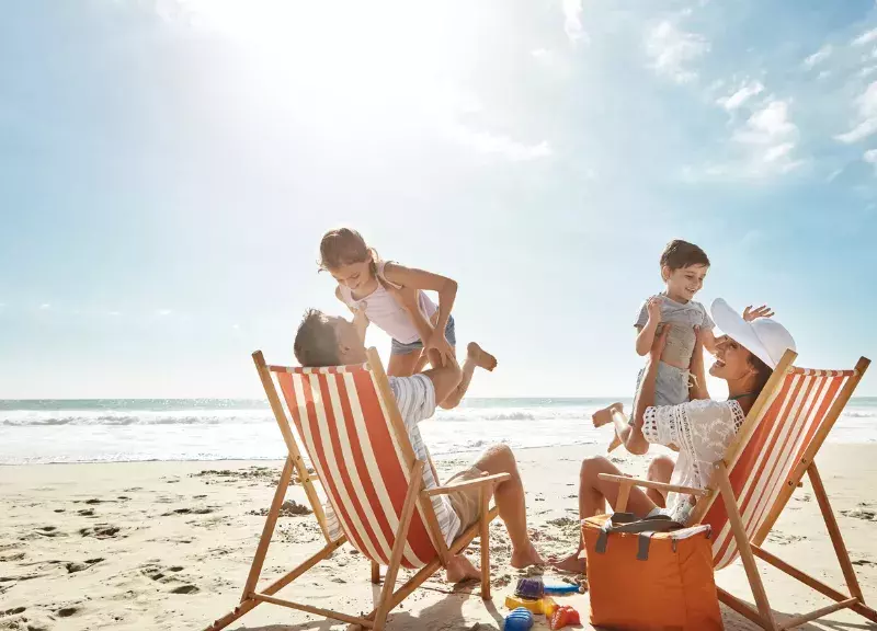 Family of four laughing on the beach. 