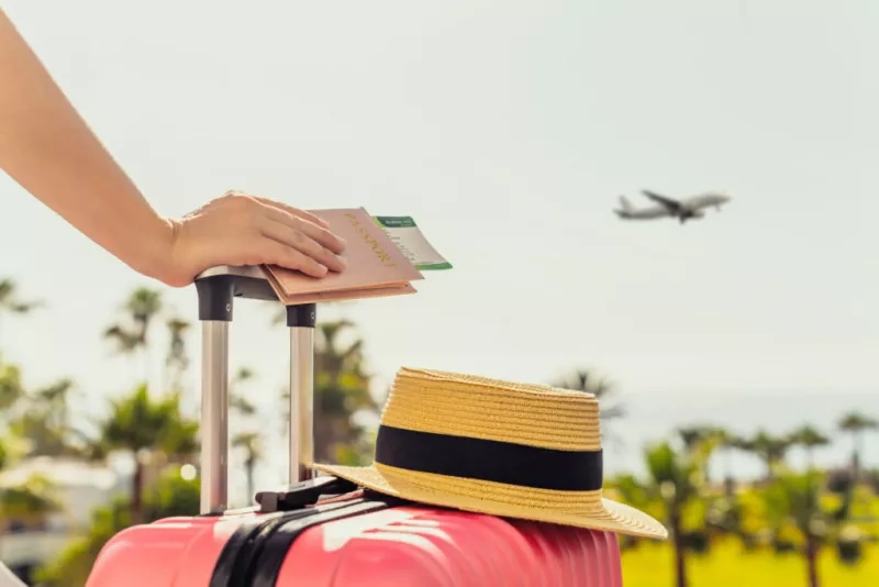 Traveler leaning on their wheely luggage